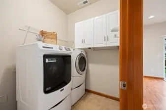There is a full capacity washer and dryer that remain with the sale of the home, as well as good cabinet storage and a hanging rack.