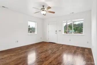 The living room from another angle proves it’s not just a pass-through space, it’s the heart of this 1,368 square foot home. The front door and double windows pull in light. A heat pump works quietly in the background, making sure this room is as comfortable in July as it is in January.