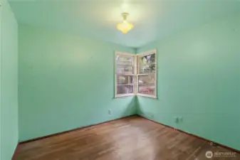 Bedroom #3 at the end of the hallway with hardwood flooring.