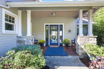 Welcome in through the covered porch with room for benches to sit and enjoy the professionally landscaped yard.
