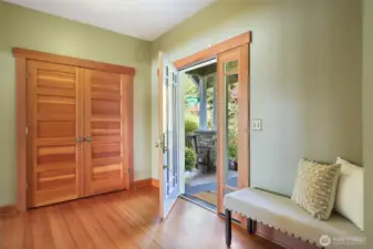 The light shines through the glass door and side windows showing off the wood trim and solid, 5 panel doors.