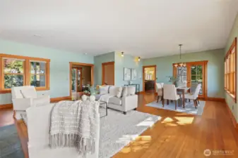 View of the living room, dining room into the kitchen. Doorway in the middle of the room leads downstairs.