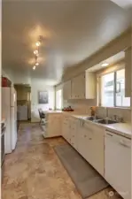 Kitchen on the right has dishwasher, double sinks with window to the backyard, lots of cabinets, freshly painted, small table with window to the backyard.