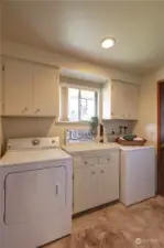 Laundry room with door to the backyard, lots of cabinets and window to the sideyard