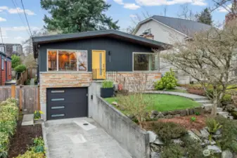 Striking modern Bryant façade with updated cement board siding, custom stonework, and a bold architectural entry that sets a confident tone. Low-maintenance turf enhances the elevated front yard, while the updated garage door and earthquake retrofit reflect thoughtful investment in both design and durability.