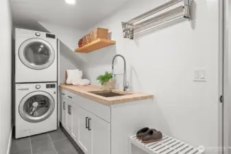 Dedicated utility room featuring stacked LG washer and dryer, custom cabinetry, and a butcher block folding counter with integrated utility sink. Designed for efficiency and organization, this space adds everyday functionality and long-term value to the home.