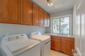 Laundry room with built-in shelving for extra storage and a convenient sink.