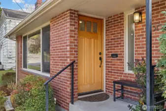 Front door to the house facing west. Covered entry. Note the statement vertical panel design, upper three-light section, exquisite hardware.