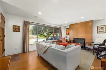 The living room features a wall of windows: fixed center picture window, and sidelights with sliding hardware and screens for fresh air.