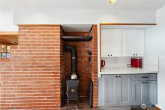 Real wood stove in kitchen on back side of living room fireplace, which is gas.