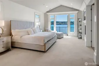 A gorgeous primary suite centered around the third gas fireplace, with more French doors leading out to a private balcony overlooking Lake Washington, Mt. Rainier and The Cascades.