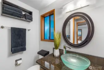 This bath, with slab granite counter and frosted glass vessel sink is next to the primary bedroom