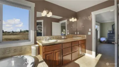 A well-designed bathroom featuring a large mirror, warm wood cabinetry, and a sightline into the bedroom.