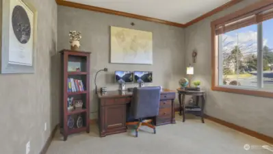 A bright and airy home office with a window wall offering serene views of nature.