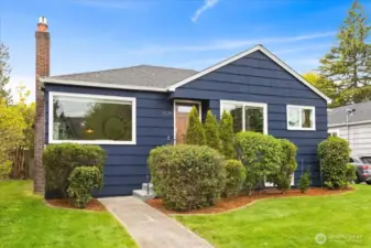 A deep navy facade, crisp white trim, and mature landscaping frame this classic West Seattle charmer.
