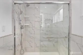 Marble-style tile, modern fixtures, and a backlit mirror elevate the ensuite bathroom experience.