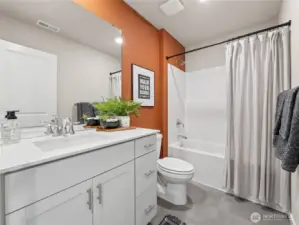 Stylish secondary bath pairs a quartz-top vanity and full tub/shower combo with a bold terracotta accent wall for designer flair. Pictures are for representational purposes only, colors and features may vary