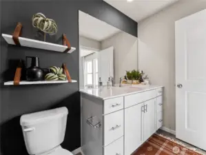 Dark accent wall with floating shelves adds designer contrast to the single-sink vanity and polished hardware. Pictures are for representational purposes only, colors and features may vary.