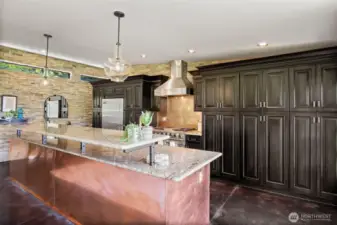 Beautiful Chef's kitchen with dark cabinets, granite countertops, copper wainscot, copper farm sink, and Viking appliances.