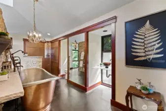 Beautiful primary bathroom area with huge copper soaking tub, vanity and shower. Beautiful finishes and striking fixtures.