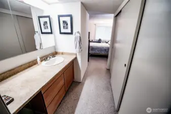View from primary bathroom looking into bedroom. New vanity/sink and tri-mirror medicine cabinet. His/her closets to right.