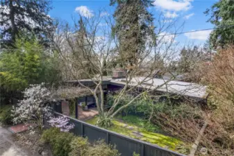 Midcentury modern home tucked into a quiet Mercer Island enclave, featuring clean architectural lines, mature landscaping, and a private corner lot setting. Fully fenced yard offers privacy and a park-like feel.