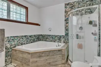 Primary bath with large jetted soaking tub and extensive accent tile work.