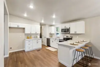 The sleek, modern kitchen boasts crisp white cabinetry, quartz countertops, stainless steel appliances.