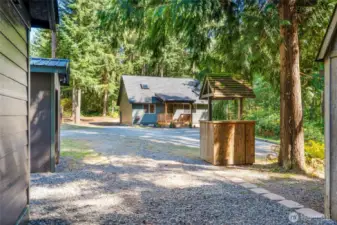 Enjoy a covered front porch, deck off the kitchen, fenced raised garden beds, storage sheds, and ample parking with room for a garage or shop
