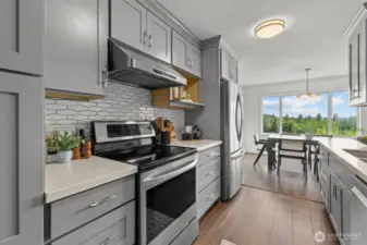 This airy galley kitchen leads to a dining space wrapped in natural light, where morning coffee comes with a view of the treetops and beyond.