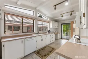 Spacious kitchen featuring large amount of storage, generous counter space. The fully covered patio is beyond the slider door at the end of the kitchen