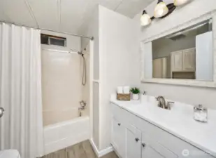 Full bathroom offers a shower/tub combo, new vanity, new LVP flooring, and modern lighting updates.  (accessories in photo virtually staged)