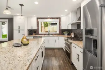 A stunning kitchen remodel with shaker cabinets, quiet-close drawers and pull-outs, granite countertops, stainless steel appliances, and a large eating island. GE dual oven and KitchenAid refrigerator.
