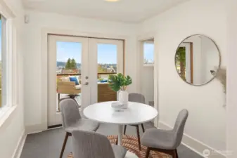 Casual eating area with French doors opening to the spacious deck with views on the Ship Canal & Olympic Mountains on a clear day.