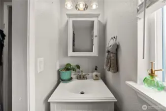 Clean and streamlined, this half bath features a crisp white vanity, framed mirror, and updated lighting—conveniently located inside the primary bedroom.