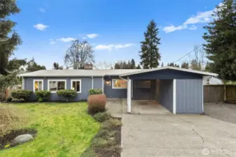 Carport with extended storage space and wide gravel area for parking and/or storage.