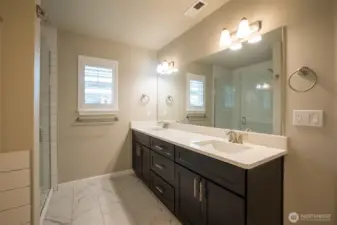 Primary bathroom with dual sinks, spacious shower is fully tiled too.