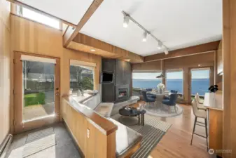 This iconic mid-century modern home, where timeless design meets breathtaking waterfront views! This area is just off the kitchen & is perfect for morning breakfast at the kitchen table, gathering area by the bench & gas fireplace.