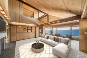 Another view of the large open living room with the breathtaking view of the water! Additional custom built-ins cozy wood burning fireplace & the Juliet balcony from the primary suite above.