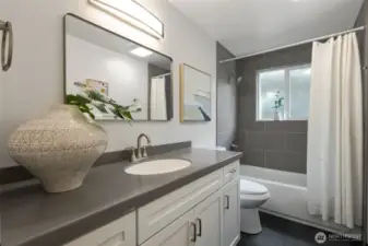 Main floor bathroom with custom cabinets & beautiful tile on the floors and the tub/shower surround.