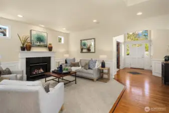 The elegant formal living room impresses with a gas fireplace, soaring ceilings, wainscoting, recessed lighting, and built-in speakers.