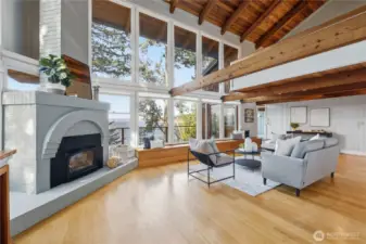 To the left as you enter through the main entrance is the wood burning fireplace and living room with soaring ceilings and wide open windows to a water view!