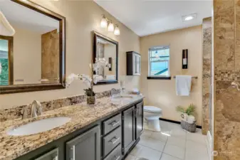 Beautifully updated primary bathroom with slab granite countertop and tile flooring.  Stunning tile walk-in shower to the right of photo. Walk-in-closet is to the left of this photo.
