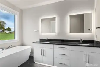 Luxurious primary bath featuring a modern dual-sink vanity with quartz counters, backlit mirrors, and a freestanding soaking tub positioned beside a large picture window—offering a serene and spa-like retreat.