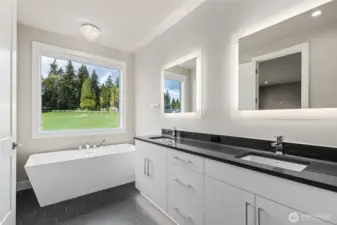 Luxurious primary bath featuring a modern dual-sink vanity with quartz counters, backlit mirrors, and a freestanding soaking tub positioned beside a large picture window—offering a serene and spa-like retreat.