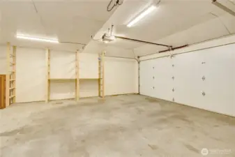 Oversized 2 car garage w/ opener, shelving and workshop behind.