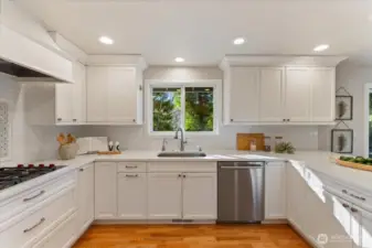 Remodeled in 2018, the kitchen showcases a Wolf range, Sub-Zero refrigerator, and Bosch dishwasher, plus a sink window framing views of the serene, private backyard.