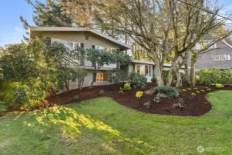 The front yard features elegant, professionally maintained landscaping accented by mature trees.