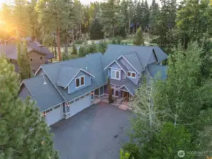 A striking aerial view of this mountain-lodge estate showcasing its welcoming front entry, generous driveway, and rare 3-car garage. Surrounded by evergreens and privacy landscaping, this home sits in the heart of Suncadia’s premier golf community.