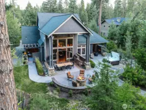 Soaring two-story windows and stunning roof lines emphasize the home's impressive architecture and indoor-outdoor connection. This angle highlights double French doors, covered dining, and the perfect flow from kitchen to firepit.